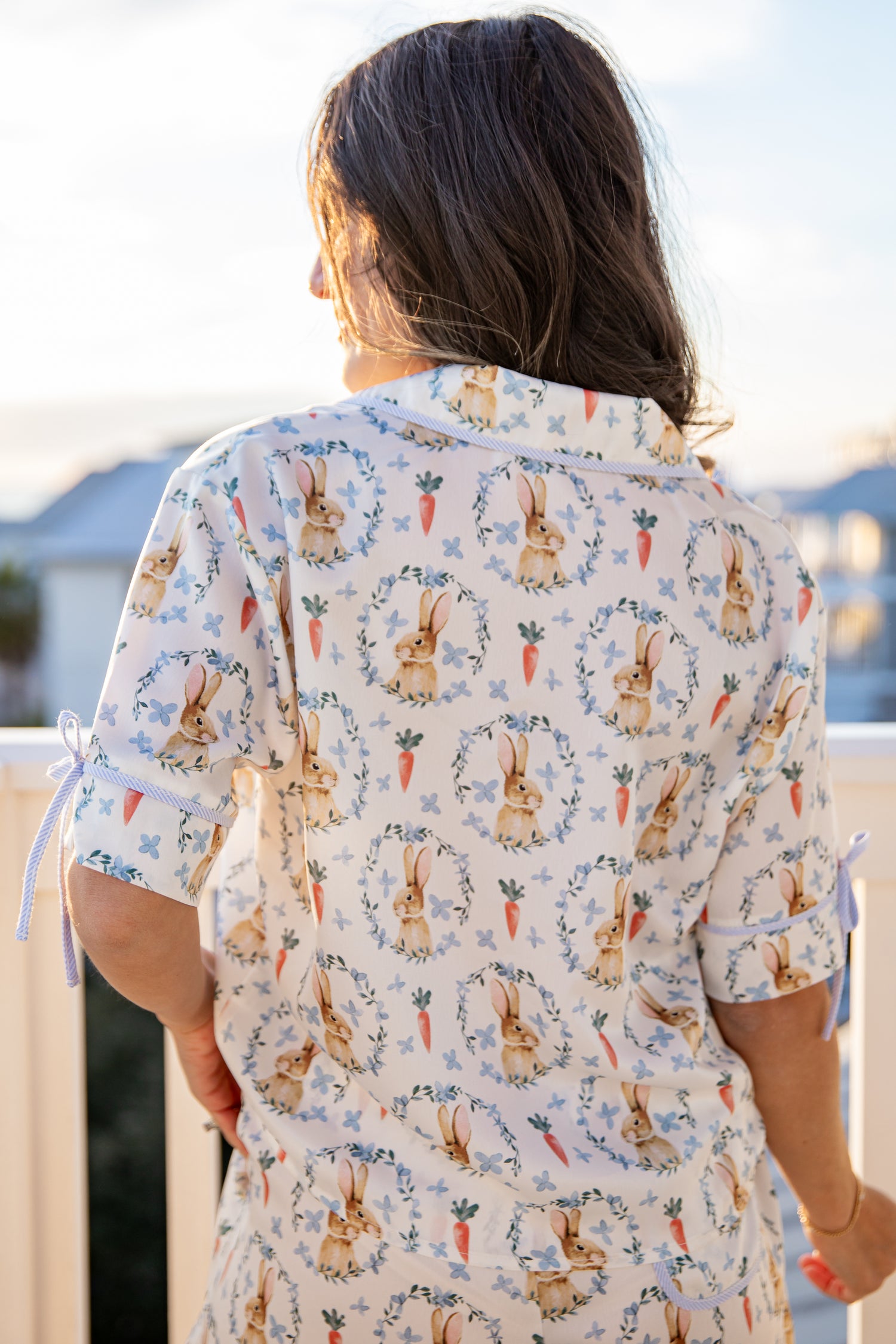 Person wearing a patterned shirt with bunnies and carrots, standing outdoors.