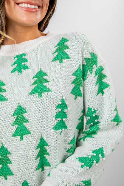 Close-up of a sweater with green tree patterns on a light background