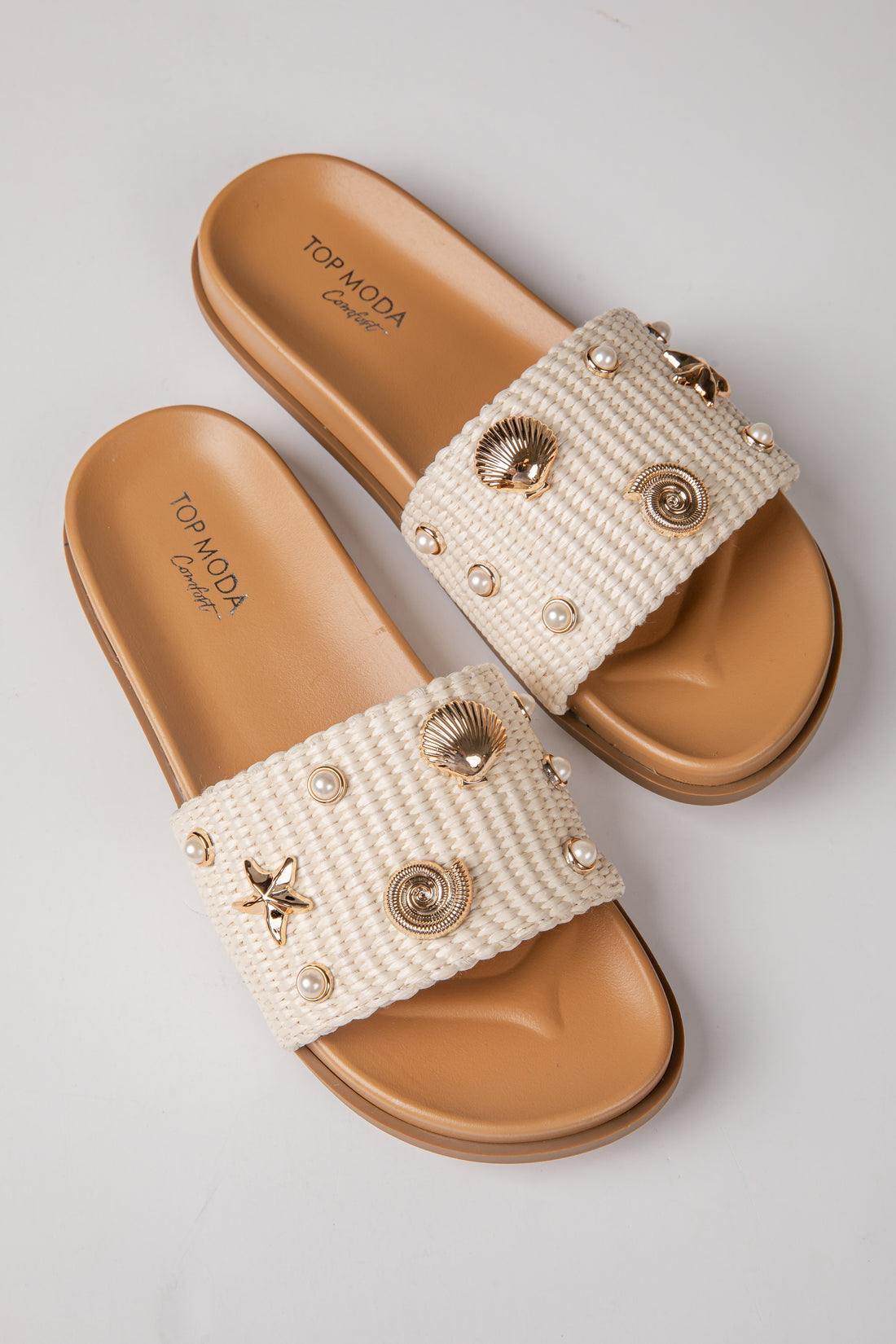 Pair of embellished sandals with beige soles on a light gray background