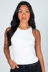 Woman wearing a white tank top against a plain background