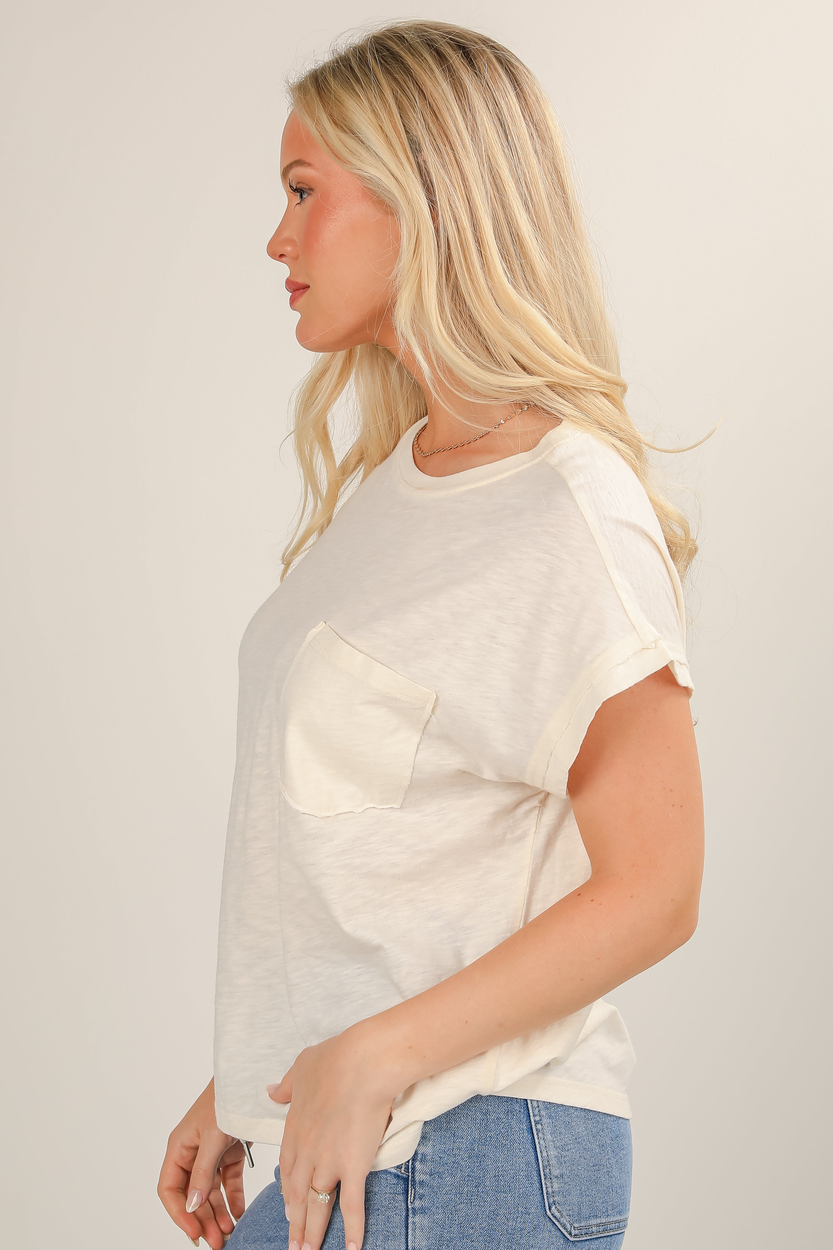 Woman wearing a white t-shirt with a pocket on a plain background