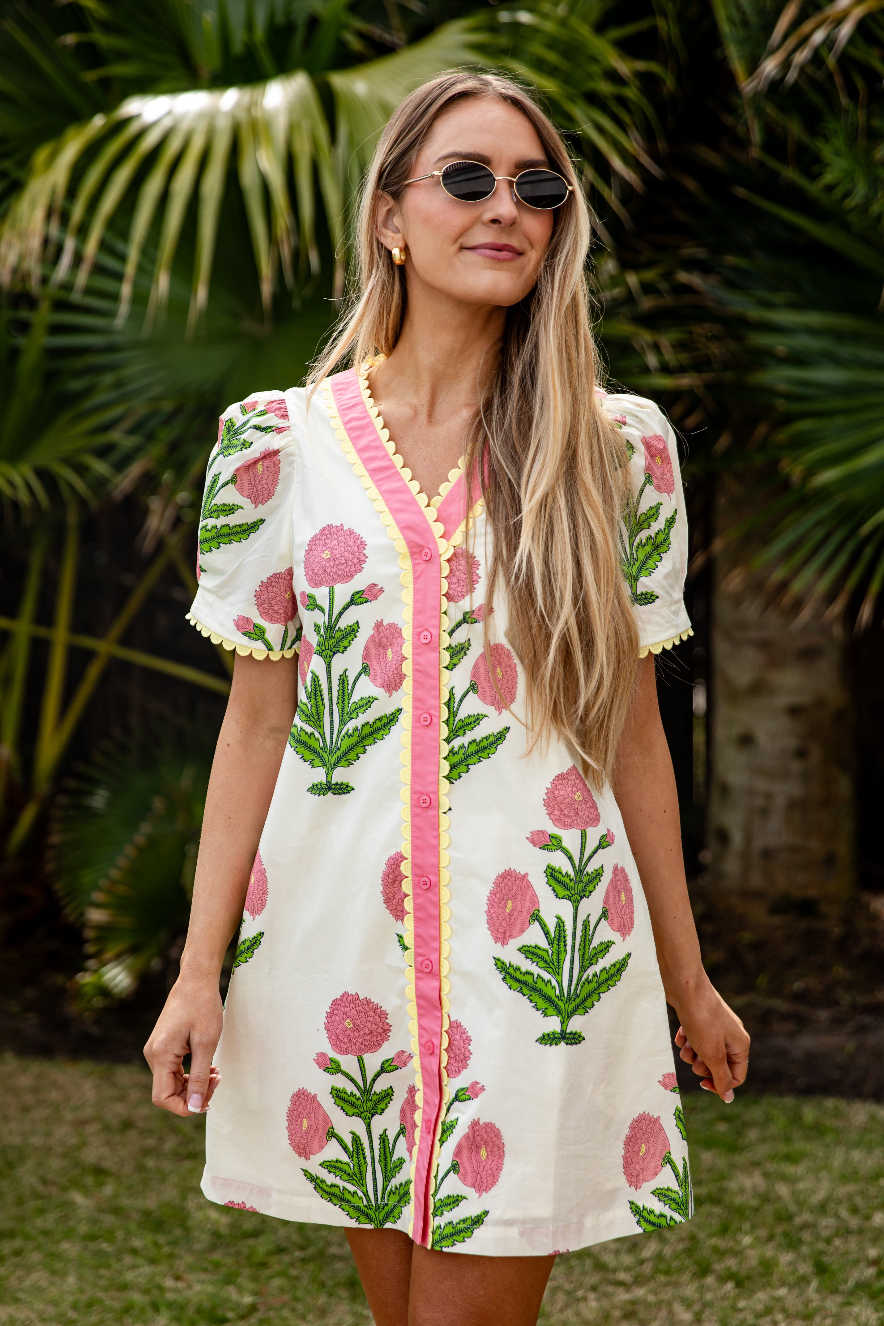 Woman wearing a floral dress with pink accents in a tropical setting