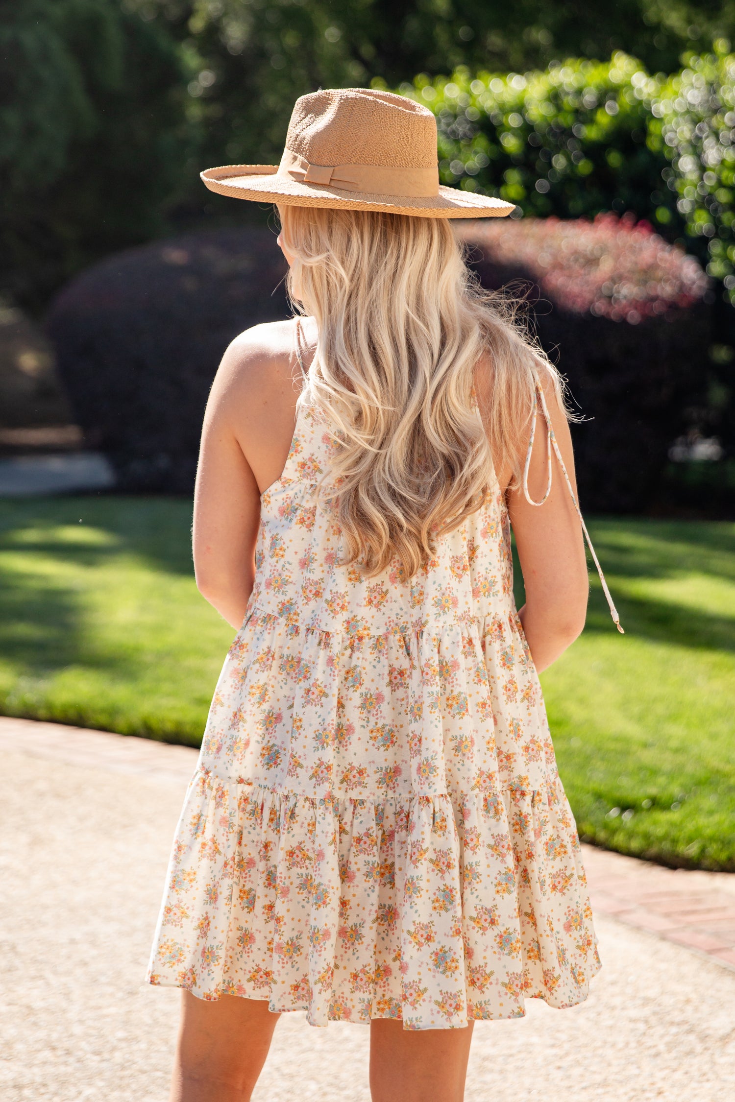 Woman wearing a floral dress and straw hat in an outdoor setting