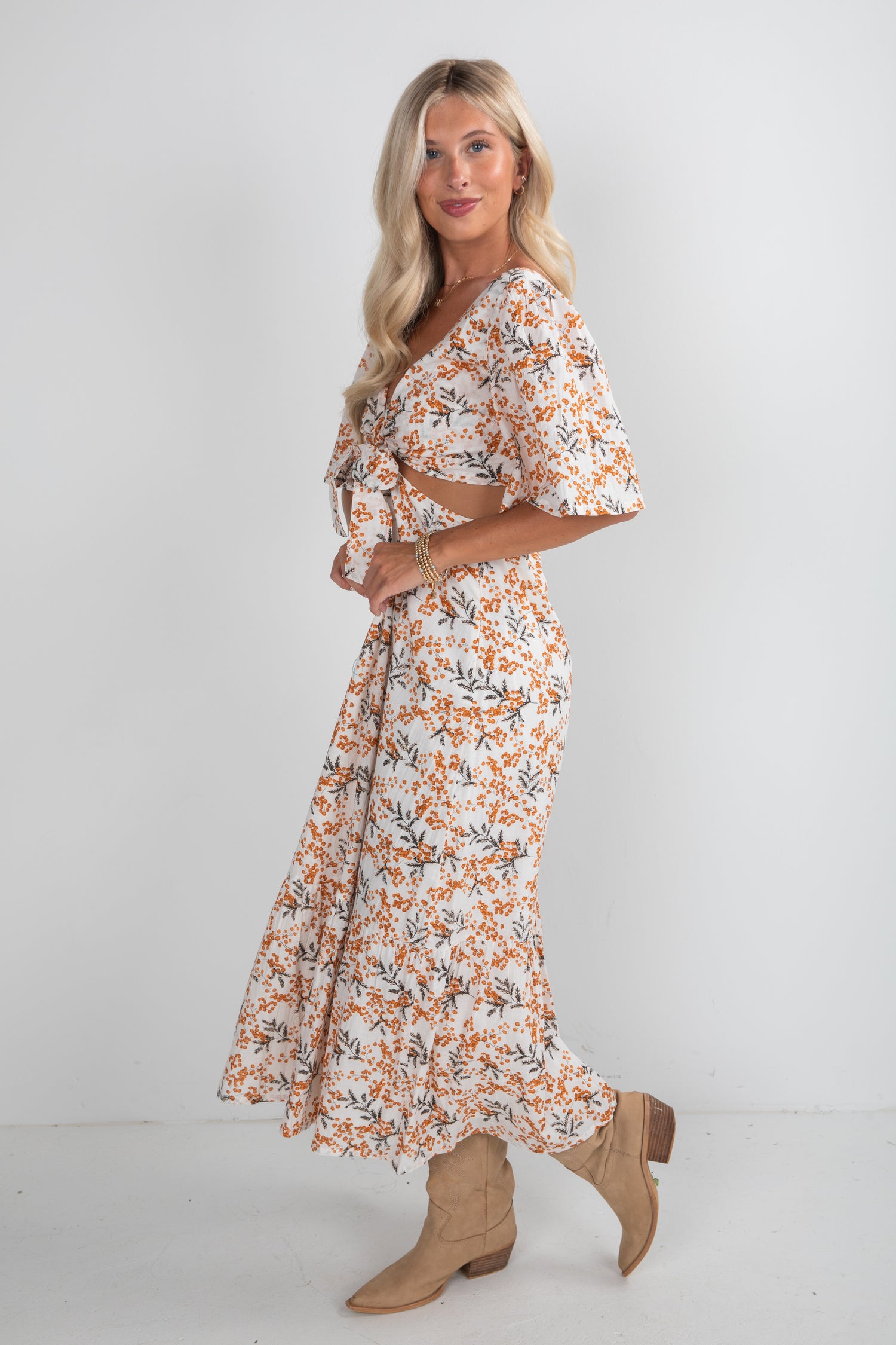Woman wearing a floral dress with beige boots on a white background
