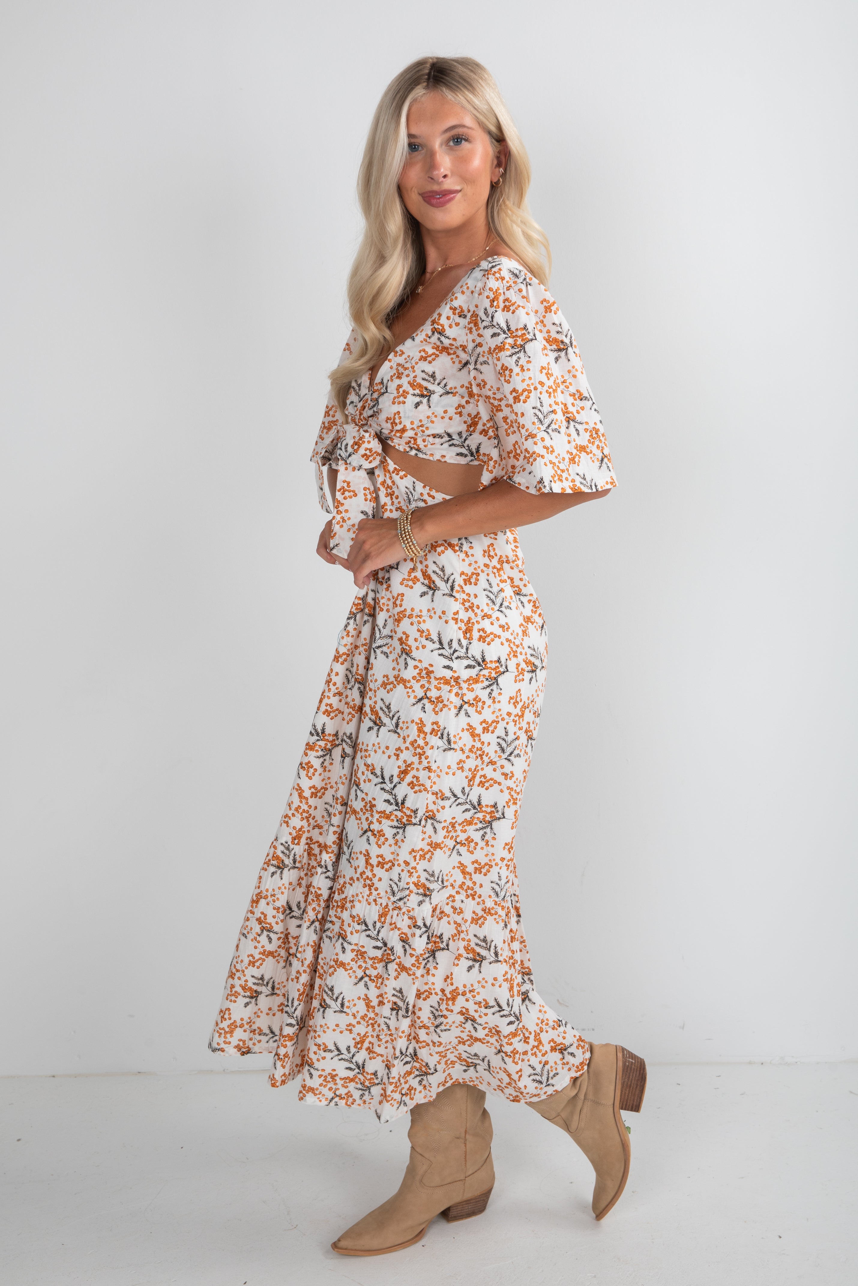 Woman wearing a floral dress with beige boots on a white background