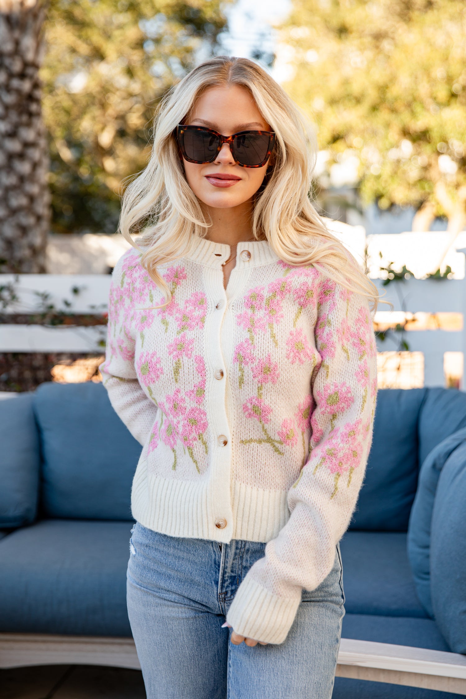 Woman wearing a floral cardigan with a blurred outdoor background
