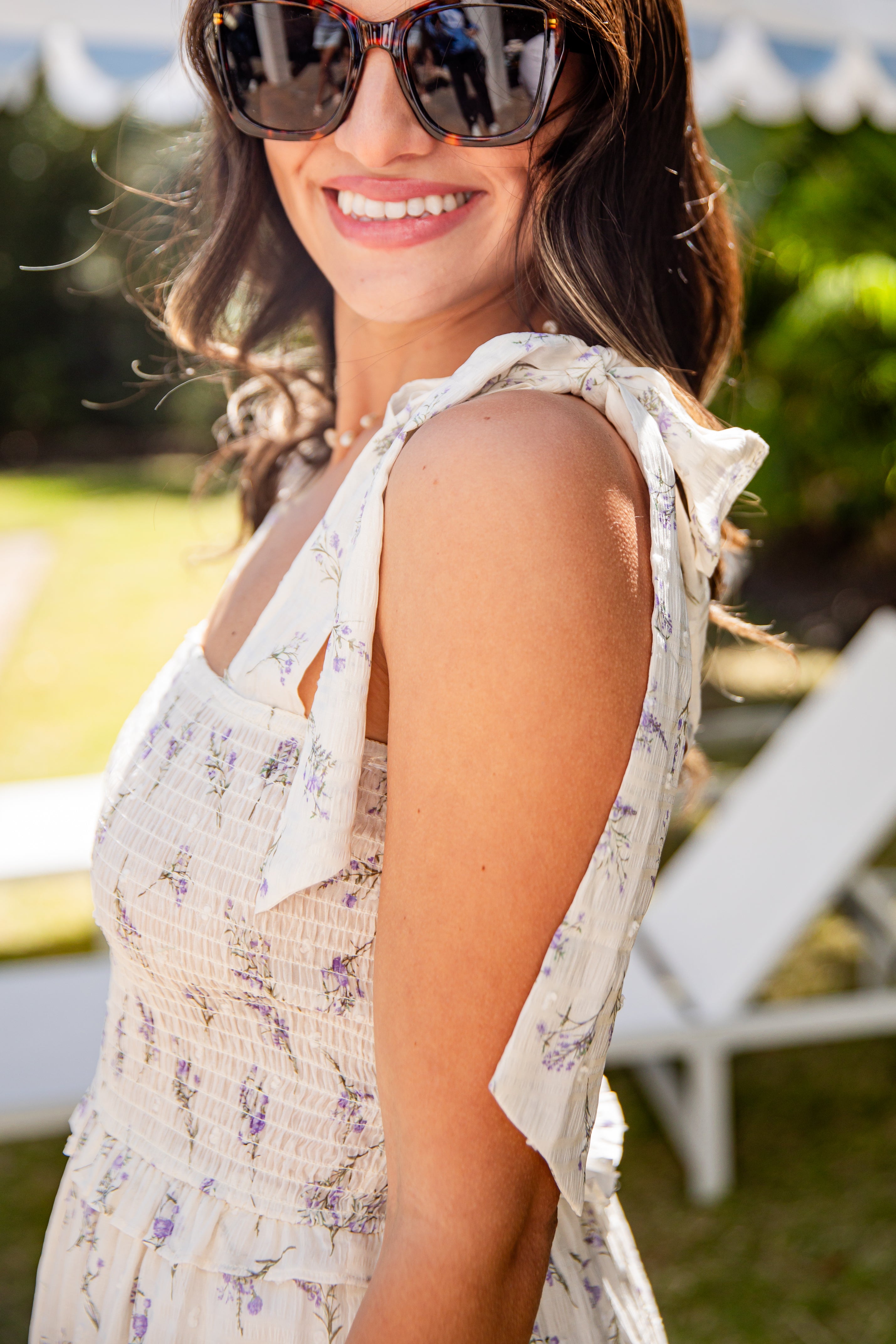 Woman wearing sunglasses and a floral dress in an outdoor setting