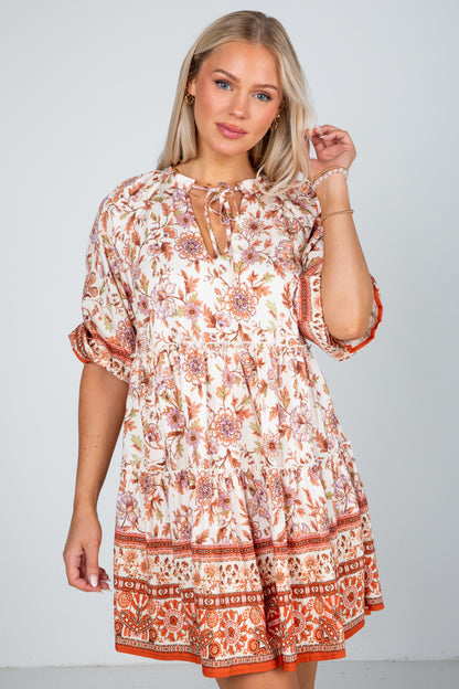 Woman wearing a patterned dress against a plain background