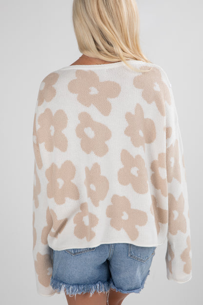 Woman wearing a beige floral-patterned sweater and denim shorts on a white background