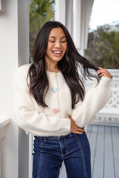 Woman wearing a white cardigan with heart patterns outdoors