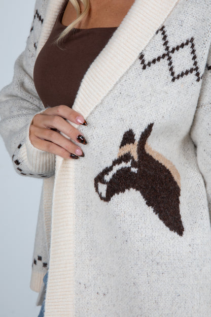 Close-up of a person wearing a cardigan with a horse design on a plain background
