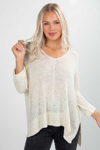 Woman wearing a cream knit sweater against a white background