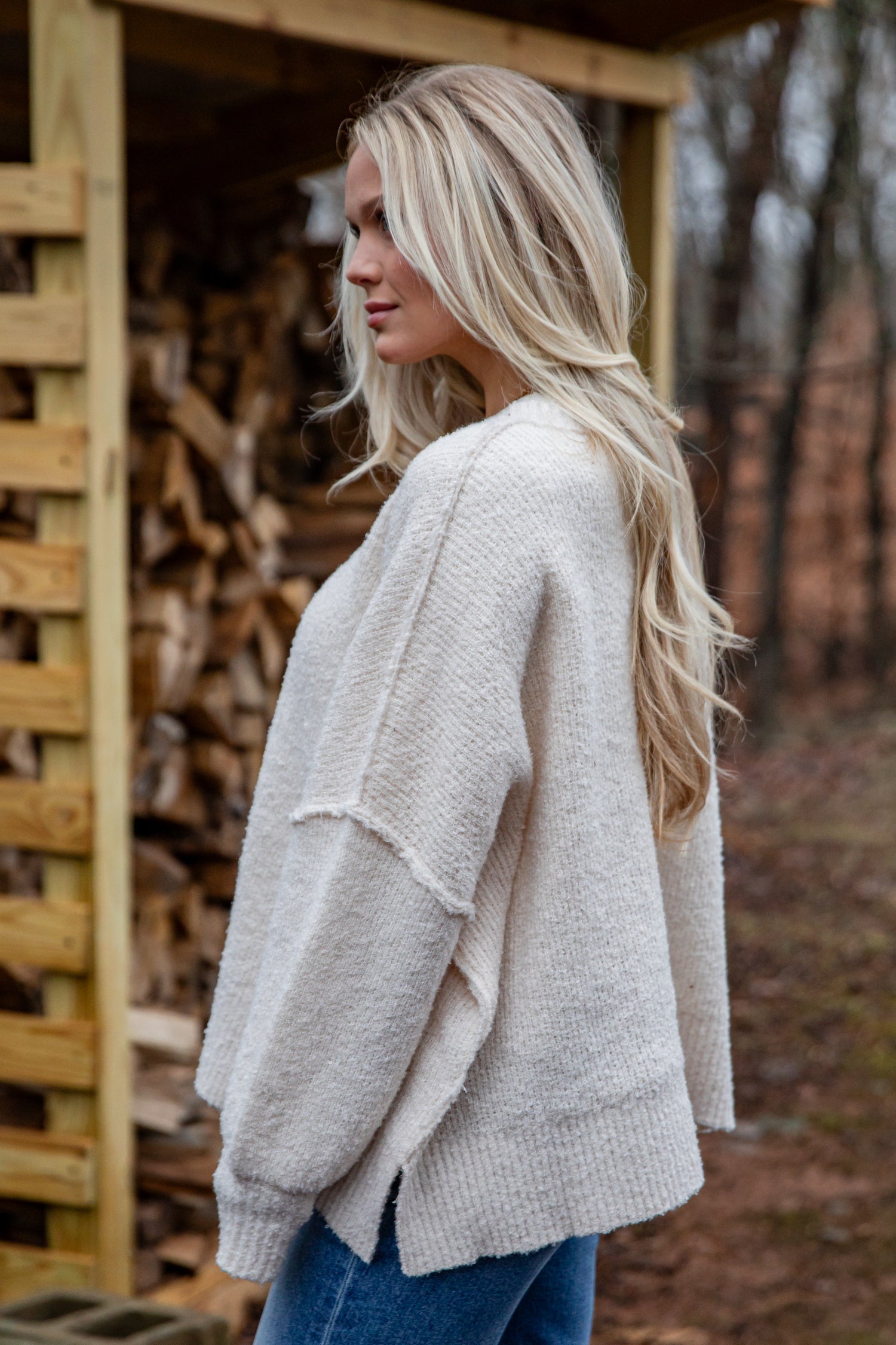 Woman wearing a beige cardigan in a forest setting