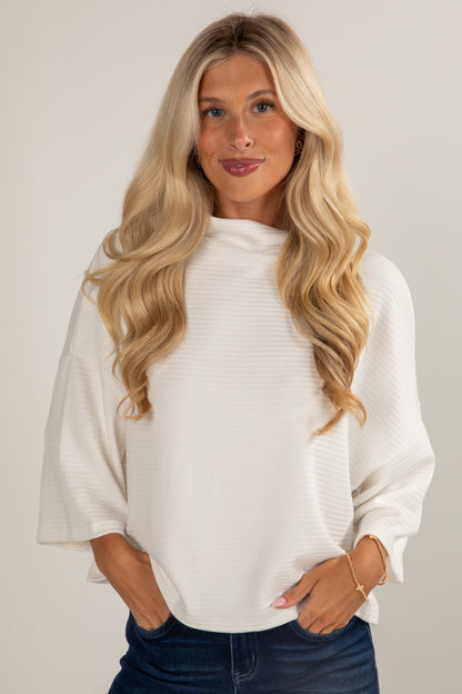 Woman wearing a white sweater with a plain background