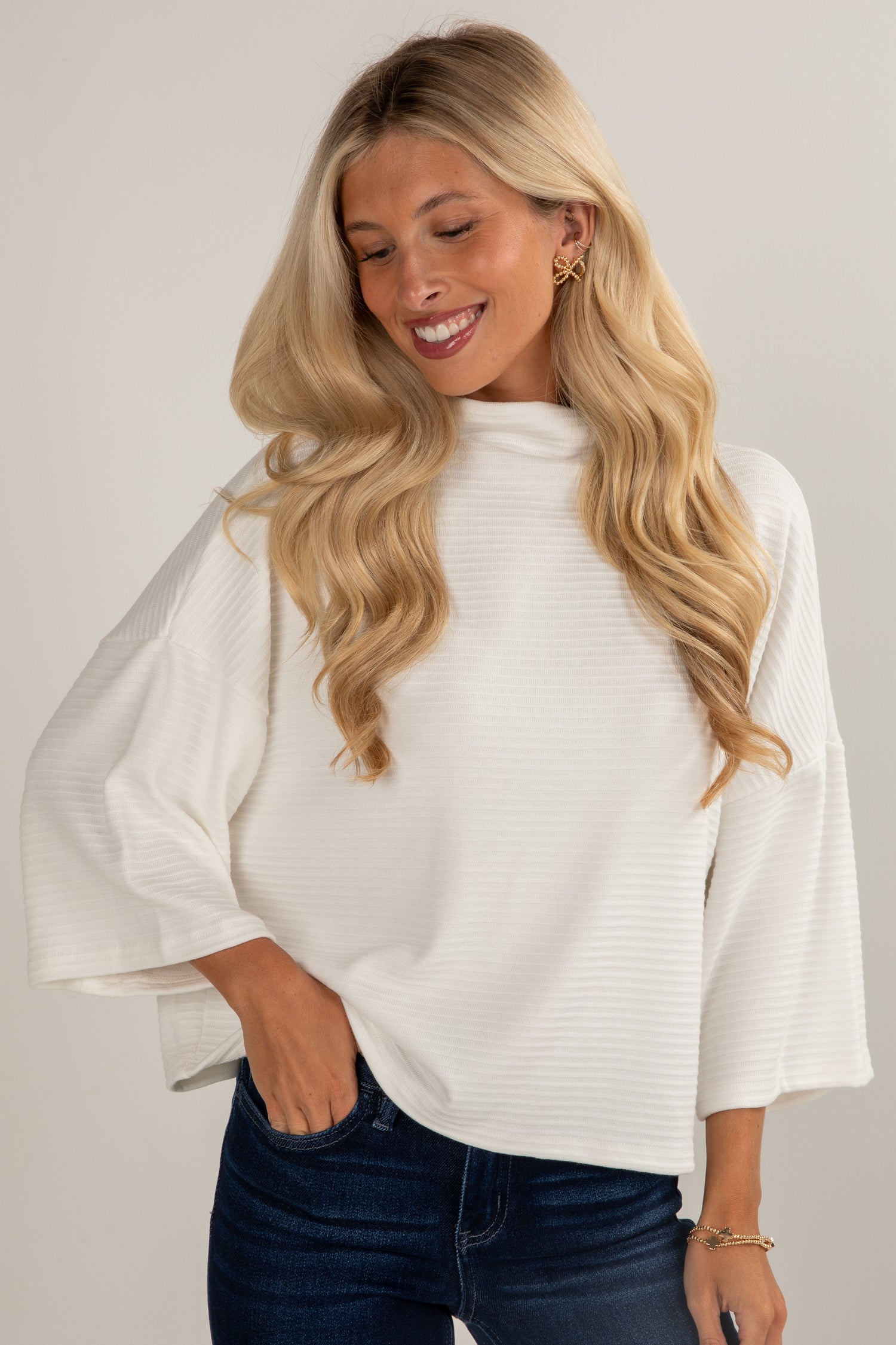 Woman wearing a white blouse with sheer sleeves against a plain background