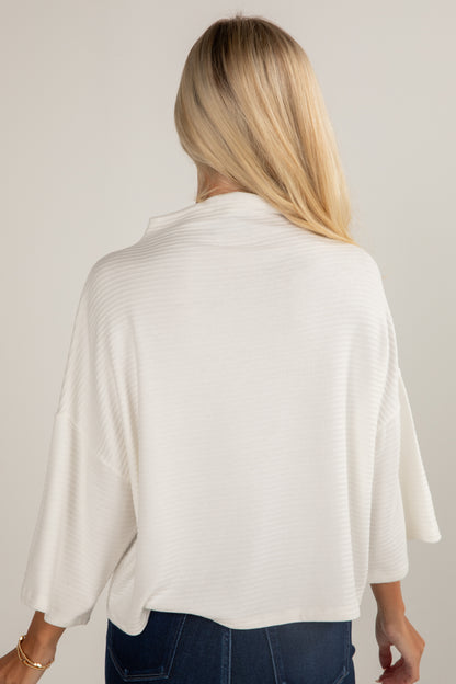 Woman wearing a white cardigan against a plain background