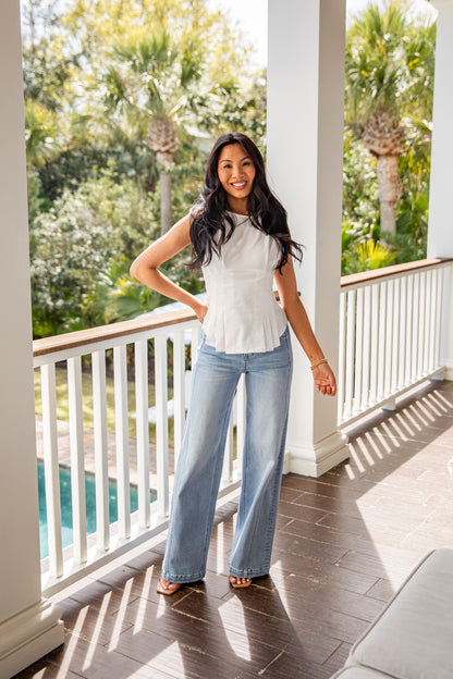Woman standing on a porch with a scenic view of trees and a pool.