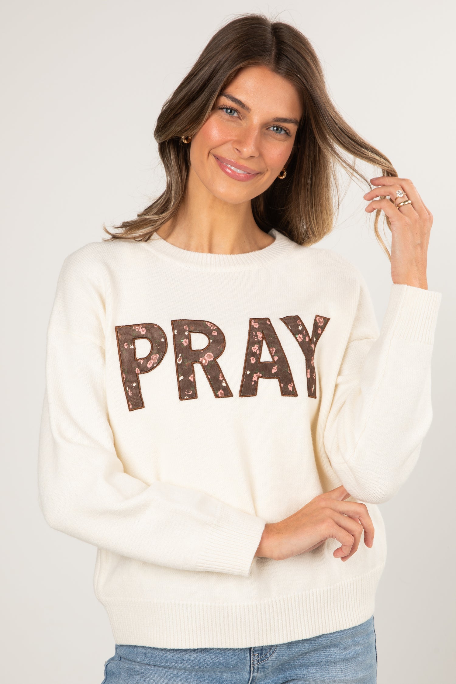 Woman wearing a cream sweater with &
