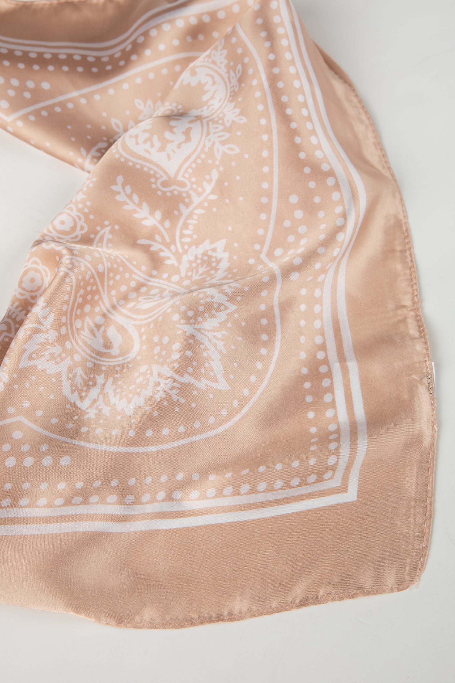 Beige scarf with white floral pattern on a light gray background