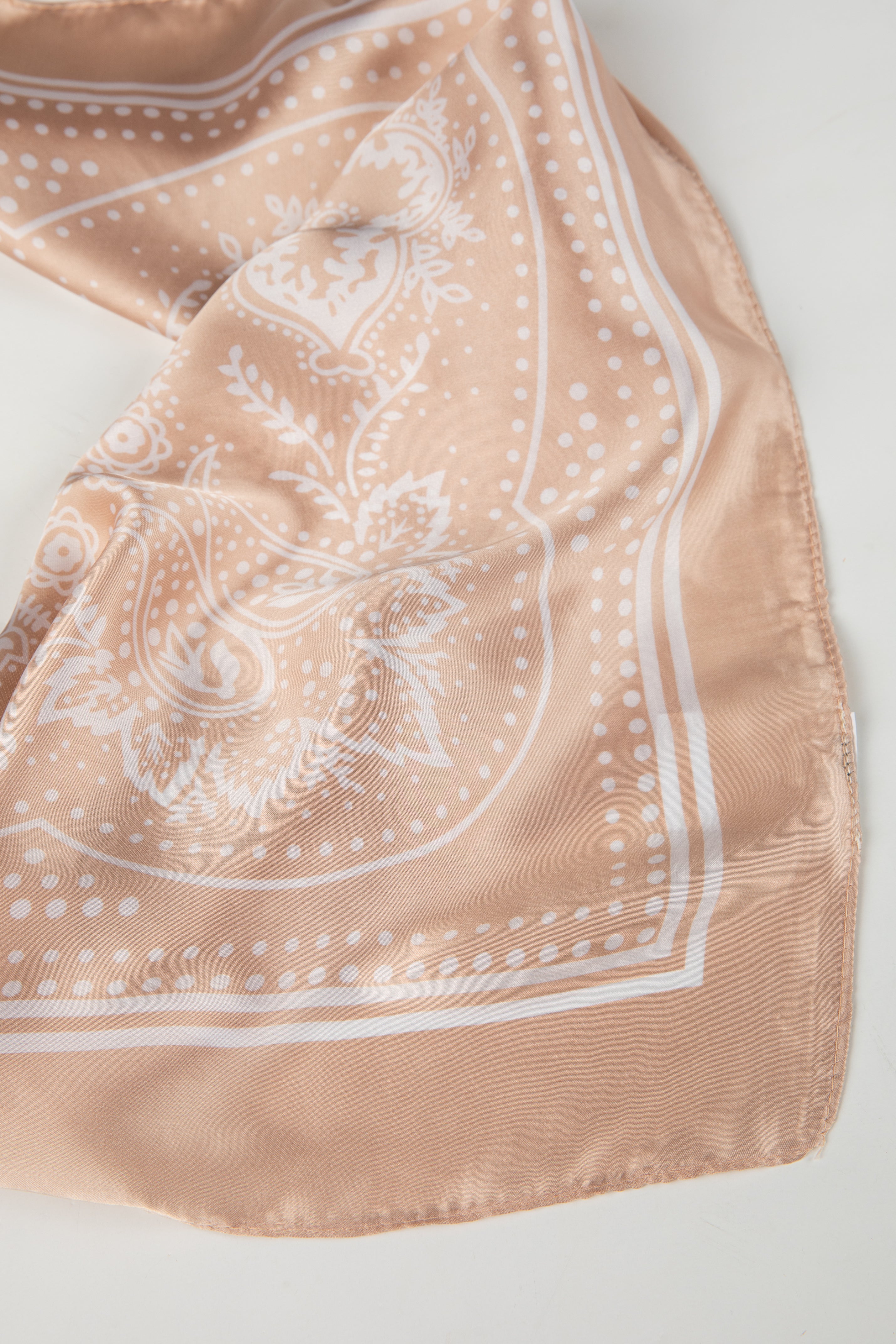 Beige scarf with white floral pattern on a light gray background