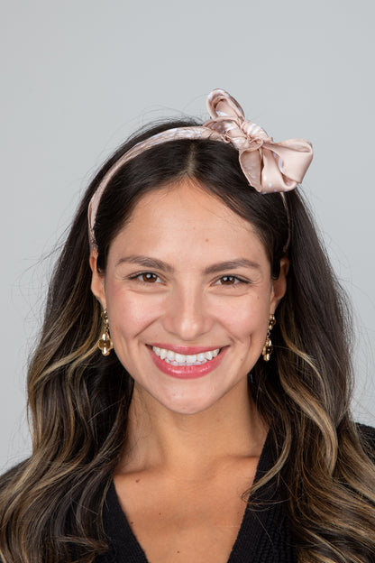 Woman wearing a pink headband with a bow against a gray background