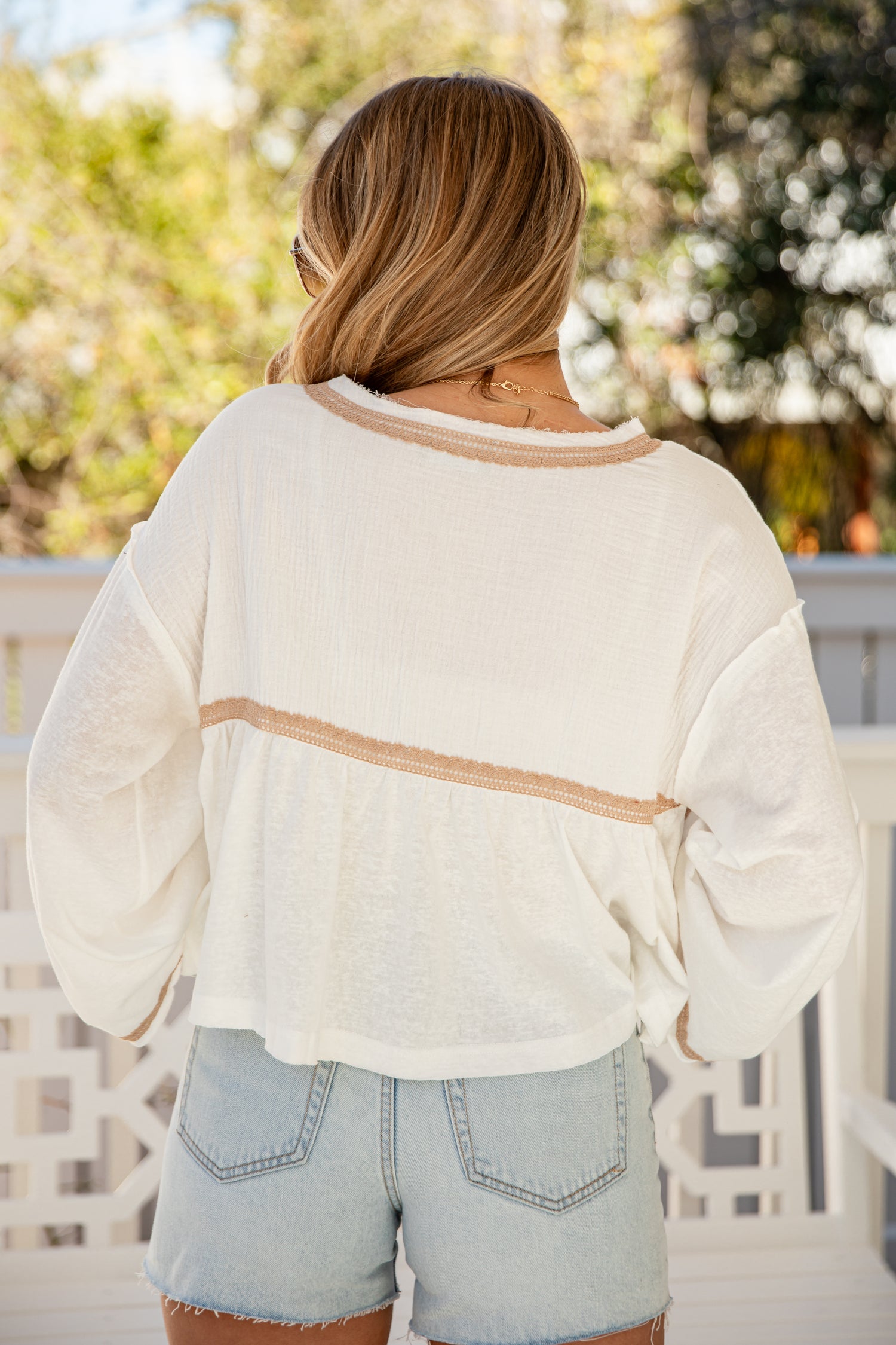 Person wearing a cream-colored sweater with a blurred outdoor background