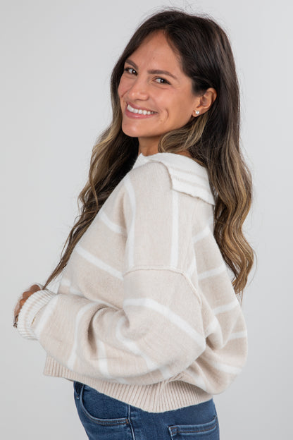 Woman wearing a cream-colored sweater with a white background