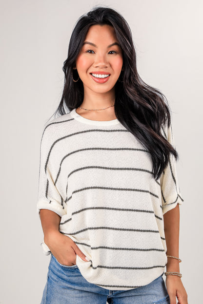 Woman wearing a striped sweater and jeans against a plain background