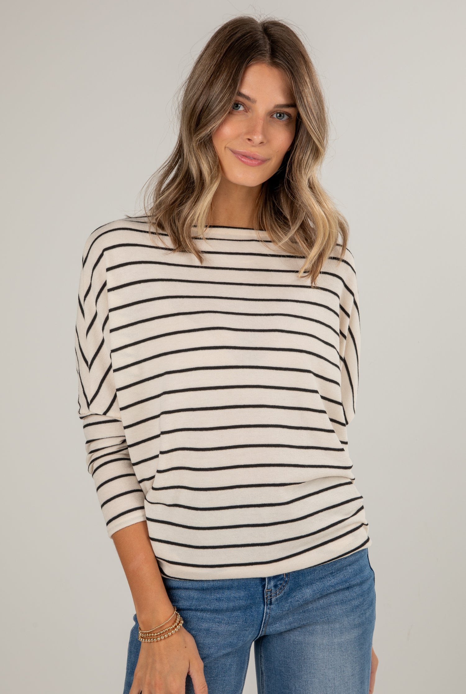 Woman wearing a striped sweater and jeans against a plain background