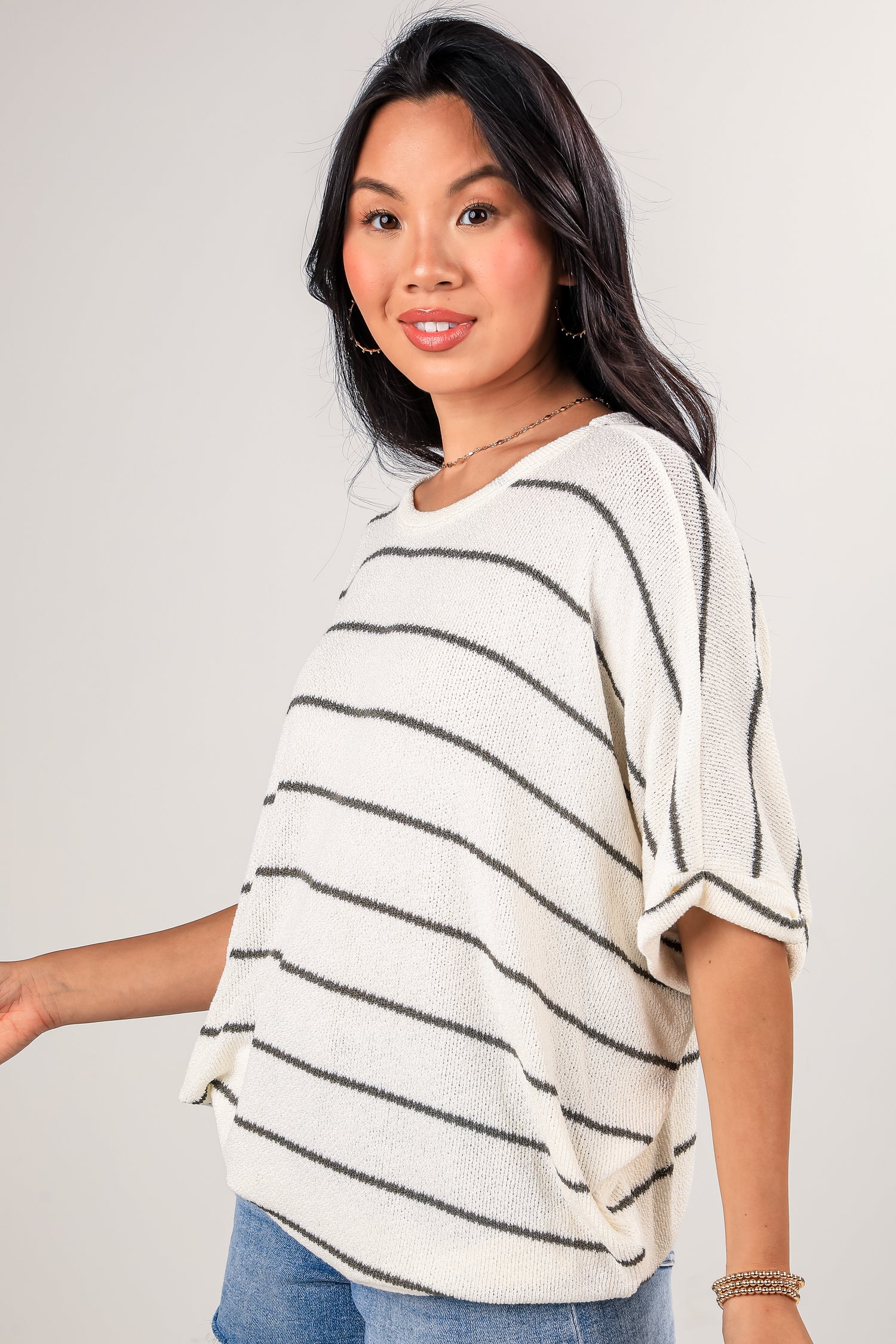 Woman wearing a white and black striped sweater against a plain background