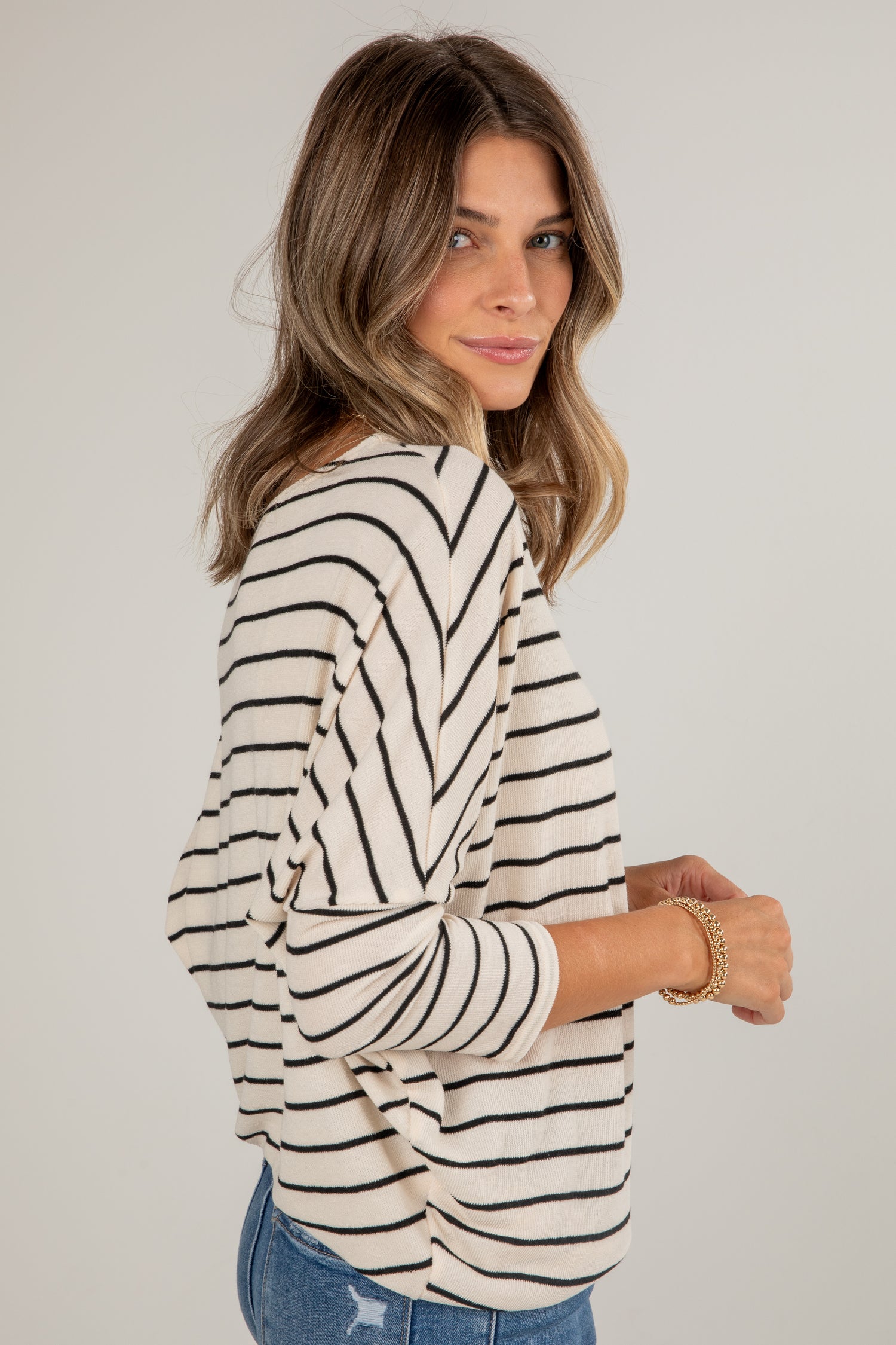 Woman wearing a black and white striped long-sleeve top on a plain background