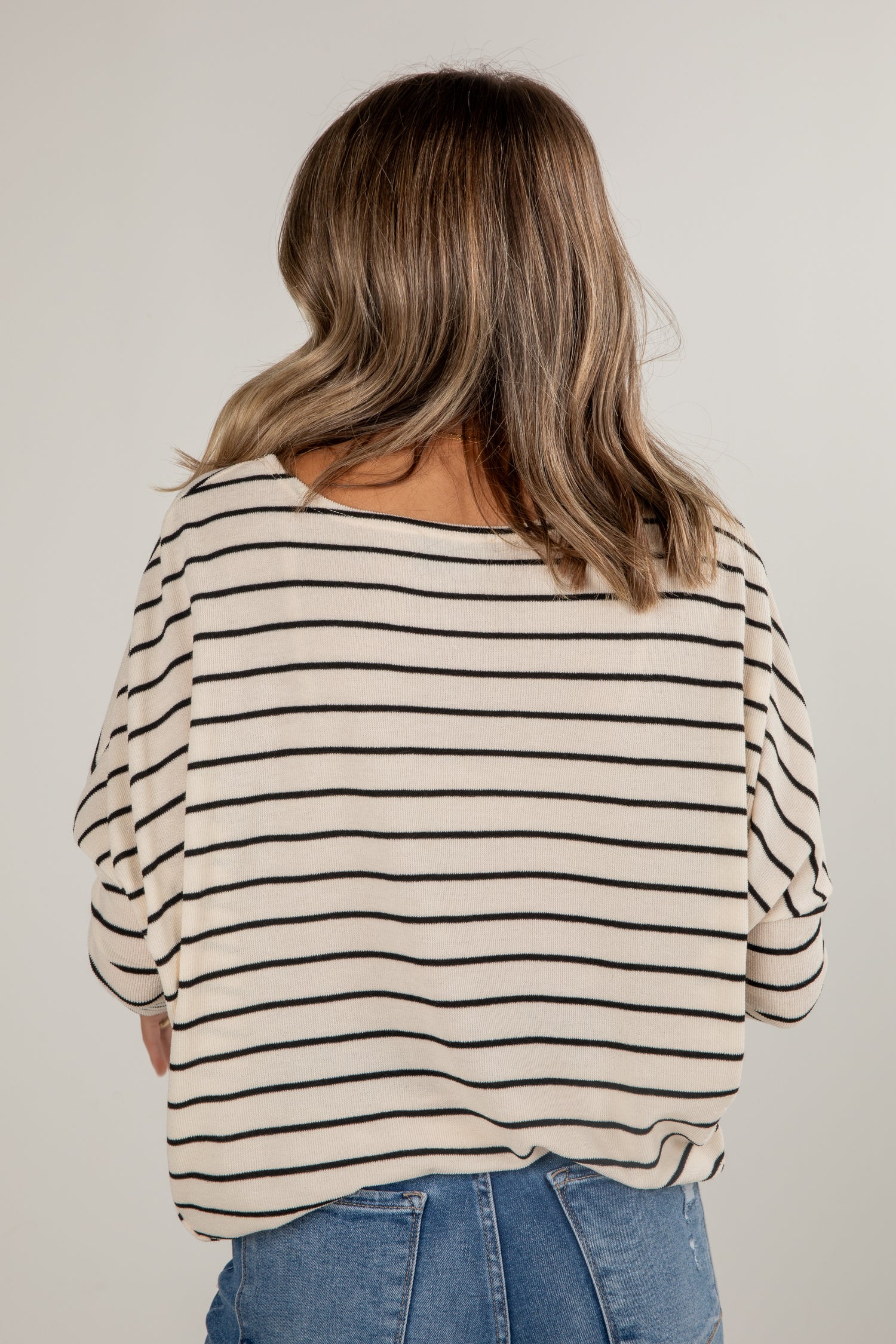 Person wearing a striped shirt and jeans against a plain background