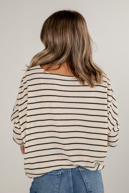 Person wearing a striped shirt and jeans against a plain background