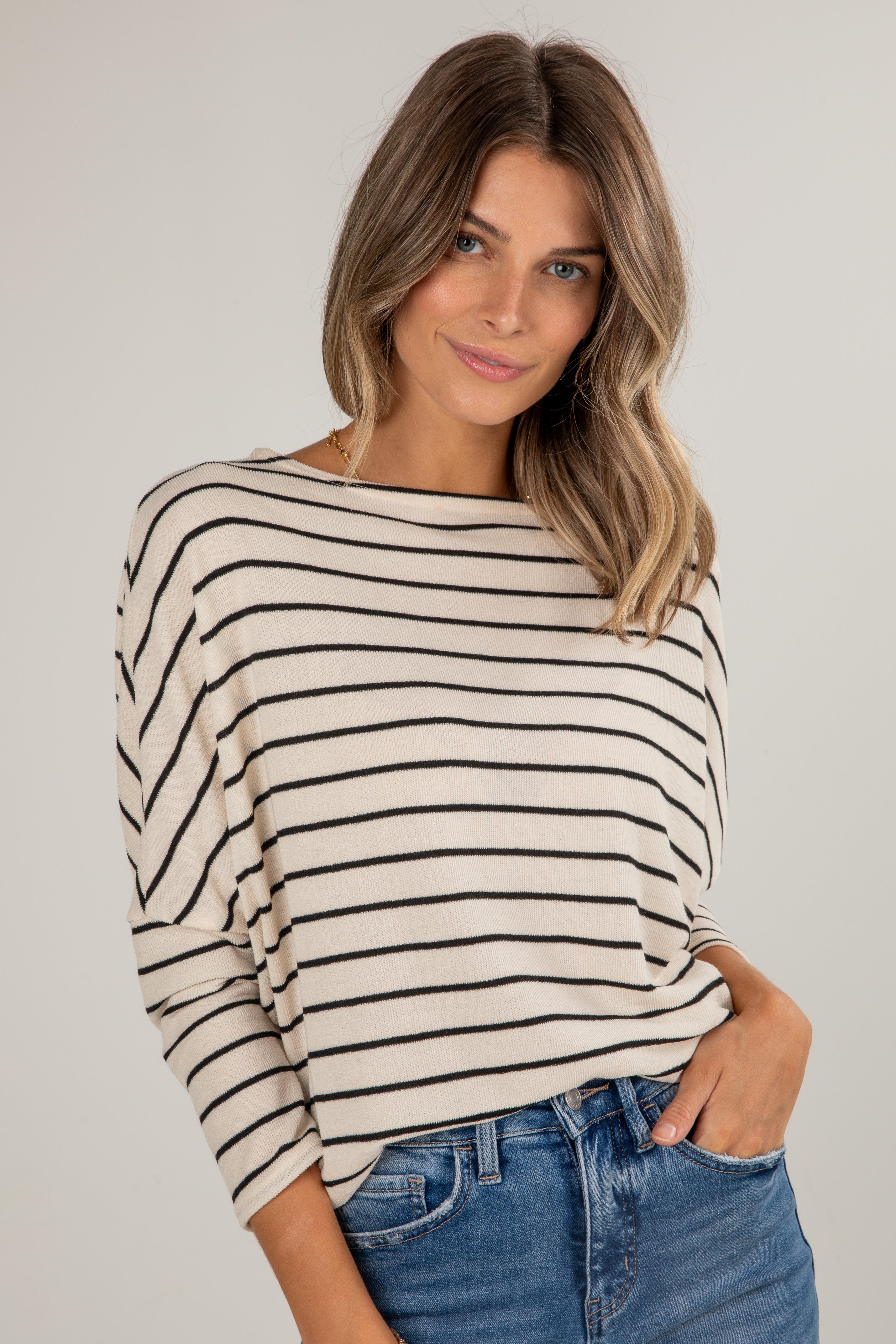 Woman wearing a striped sweater and jeans against a plain background