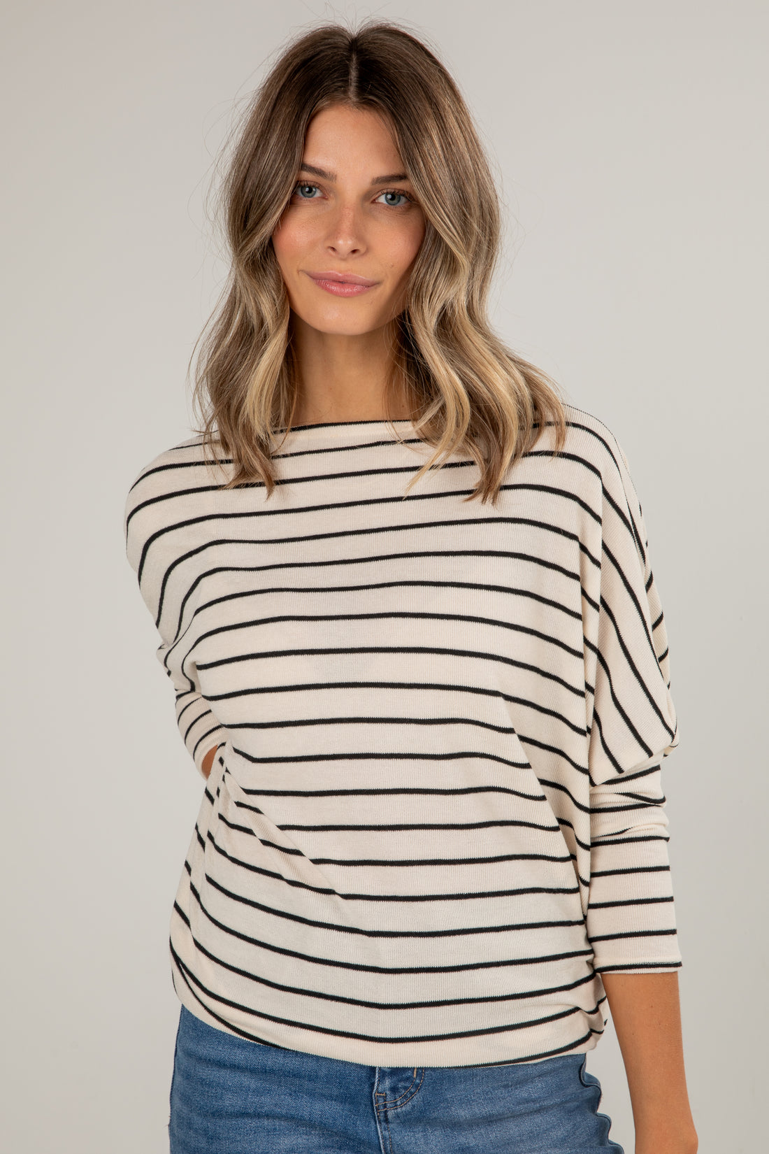 Woman wearing a black and white striped sweater against a plain background