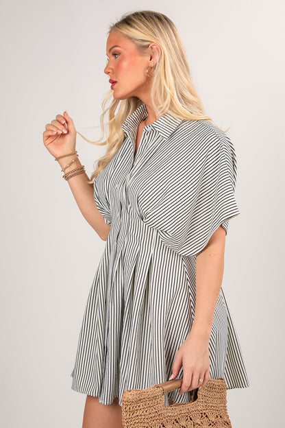 Woman wearing a striped dress holding a woven bag against a plain background