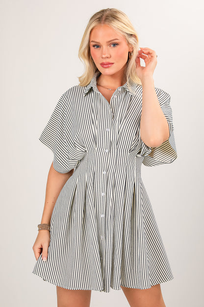Woman wearing a black and white striped shirt dress on a plain background