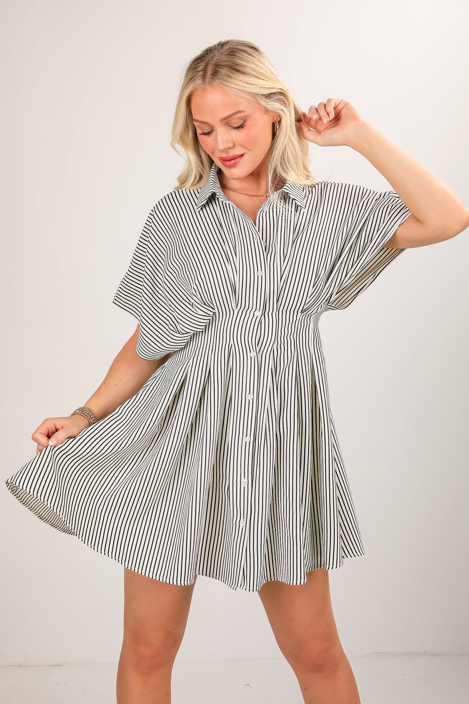 Woman wearing a striped shirt dress against a plain background