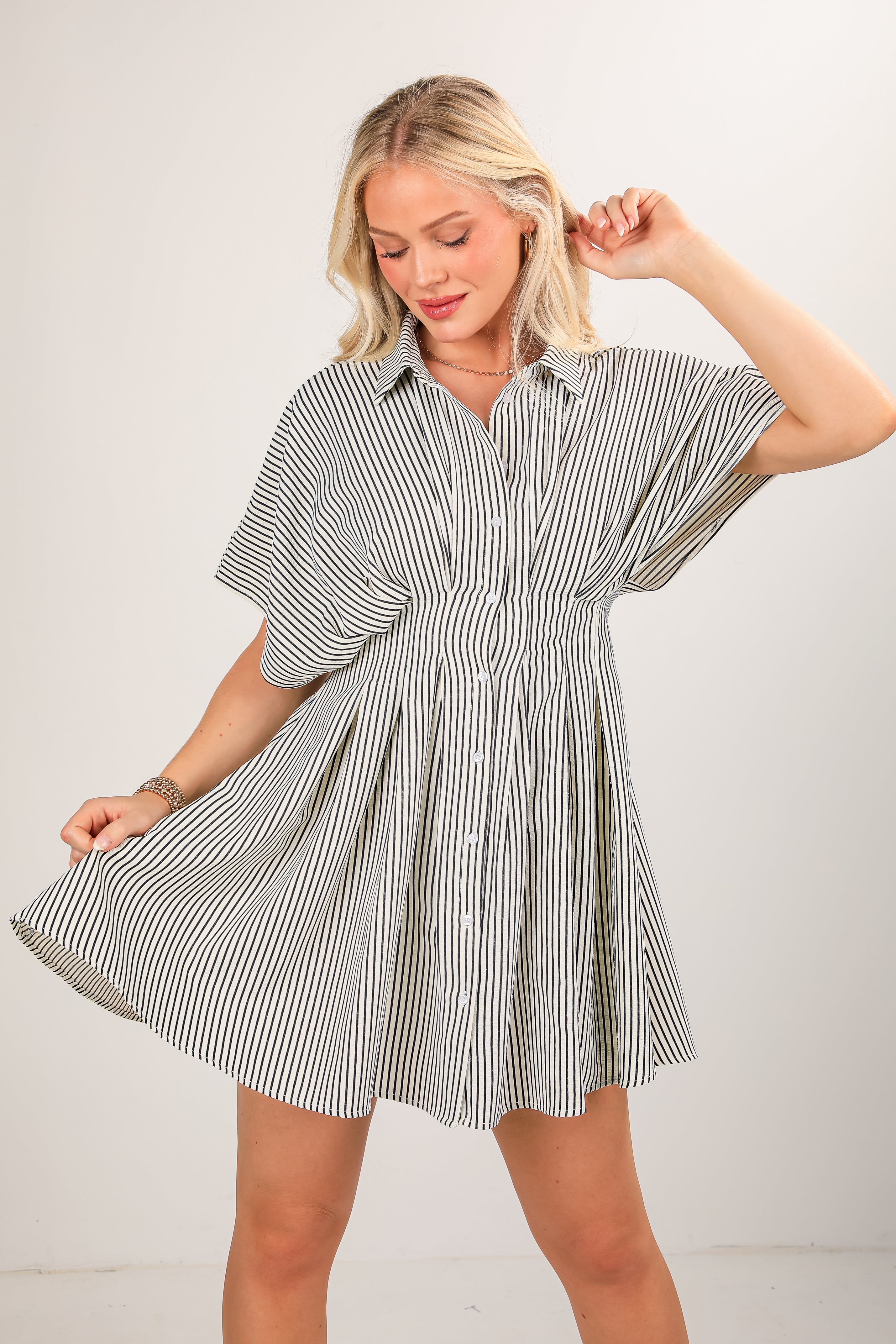 Woman wearing a striped shirt dress against a plain background