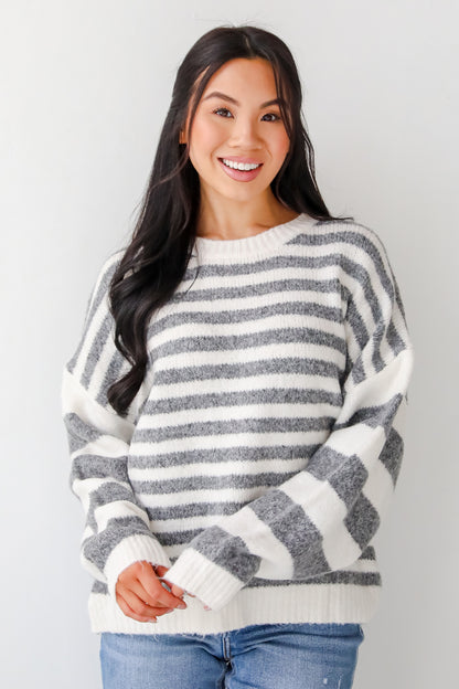 Woman wearing a gray and white striped sweater against a plain background
