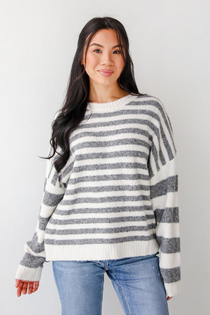 Woman wearing a striped sweater and jeans against a plain background