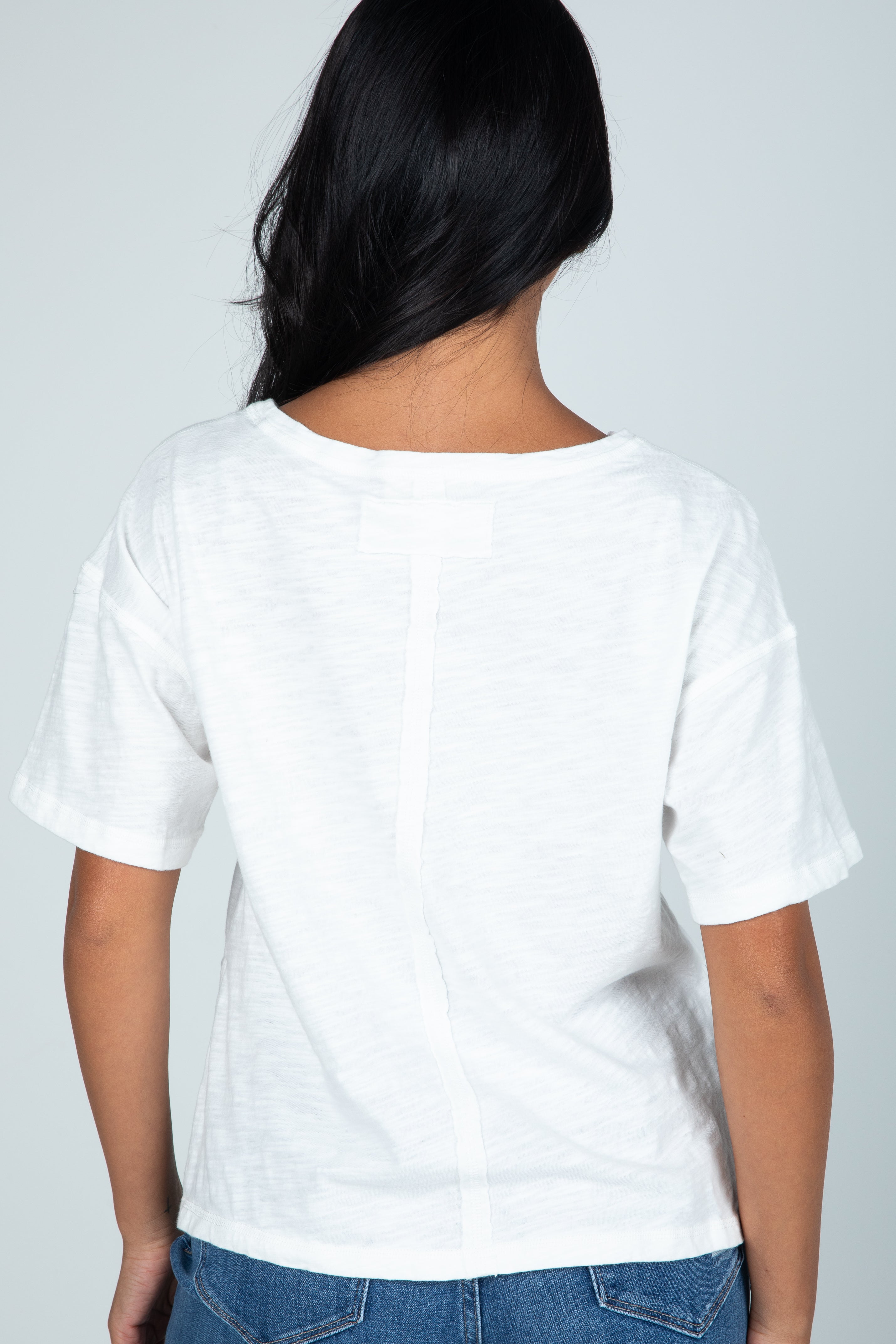 Person wearing a plain white t-shirt against a light gray background