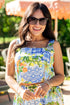 Woman wearing a colorful dress with a pattern of lemons and limes, standing outdoors under an umbrella.