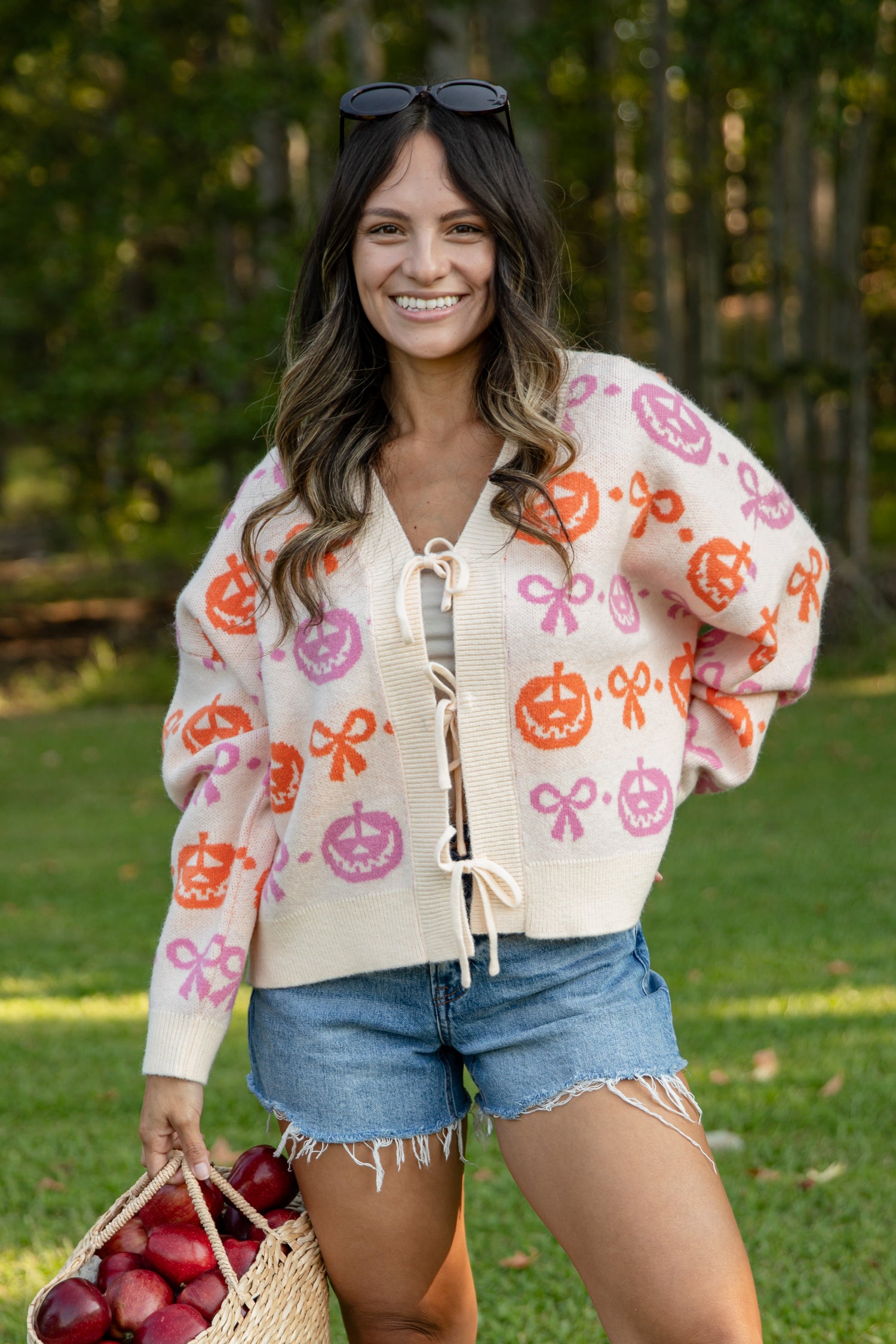 Woman wearing a patterned cardigan holding apples outdoors