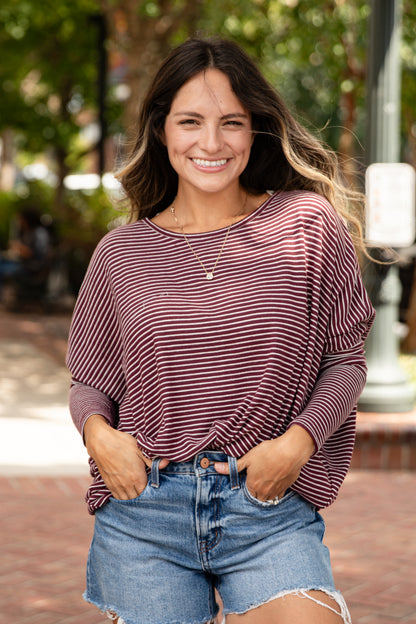 Woman wearing a striped shirt and denim shorts standing outdoors.
