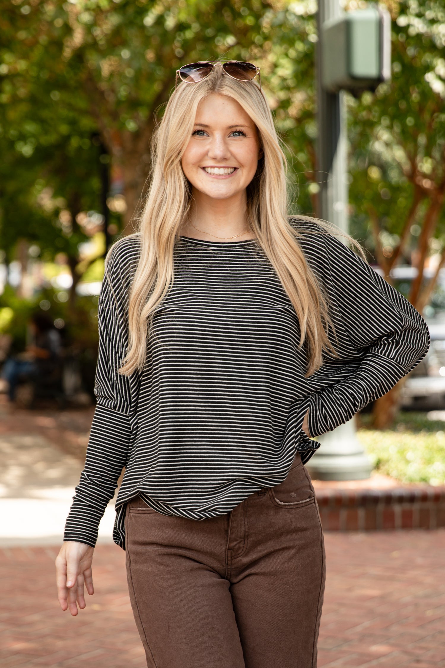 Woman wearing a striped long-sleeve top and brown pants outdoors.
