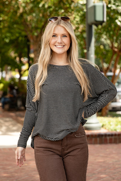 Woman wearing a striped long-sleeve top and brown pants outdoors.