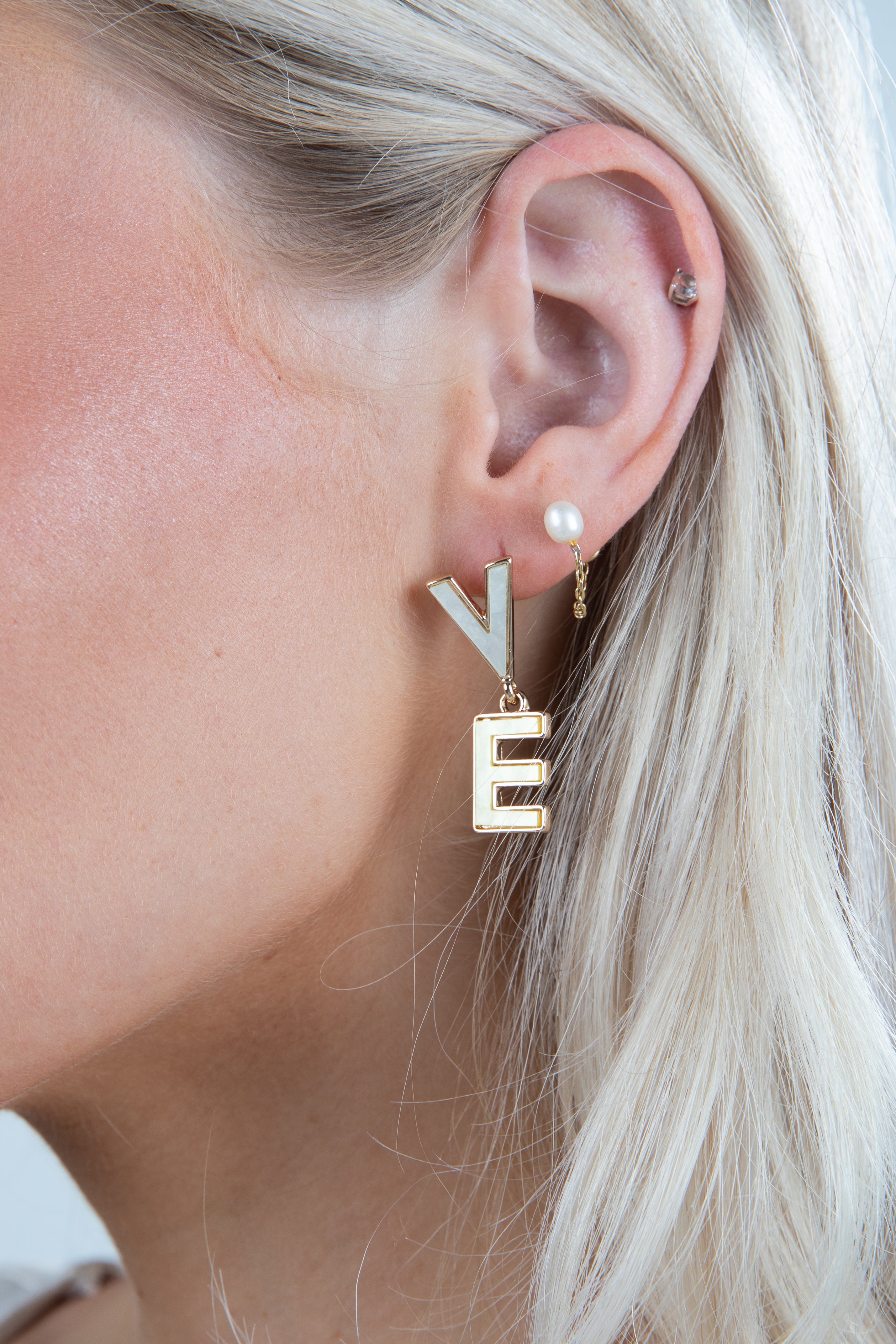 Close-up of a person wearing gold letter &