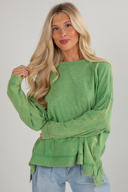 Woman wearing a green long-sleeve top with a plain background