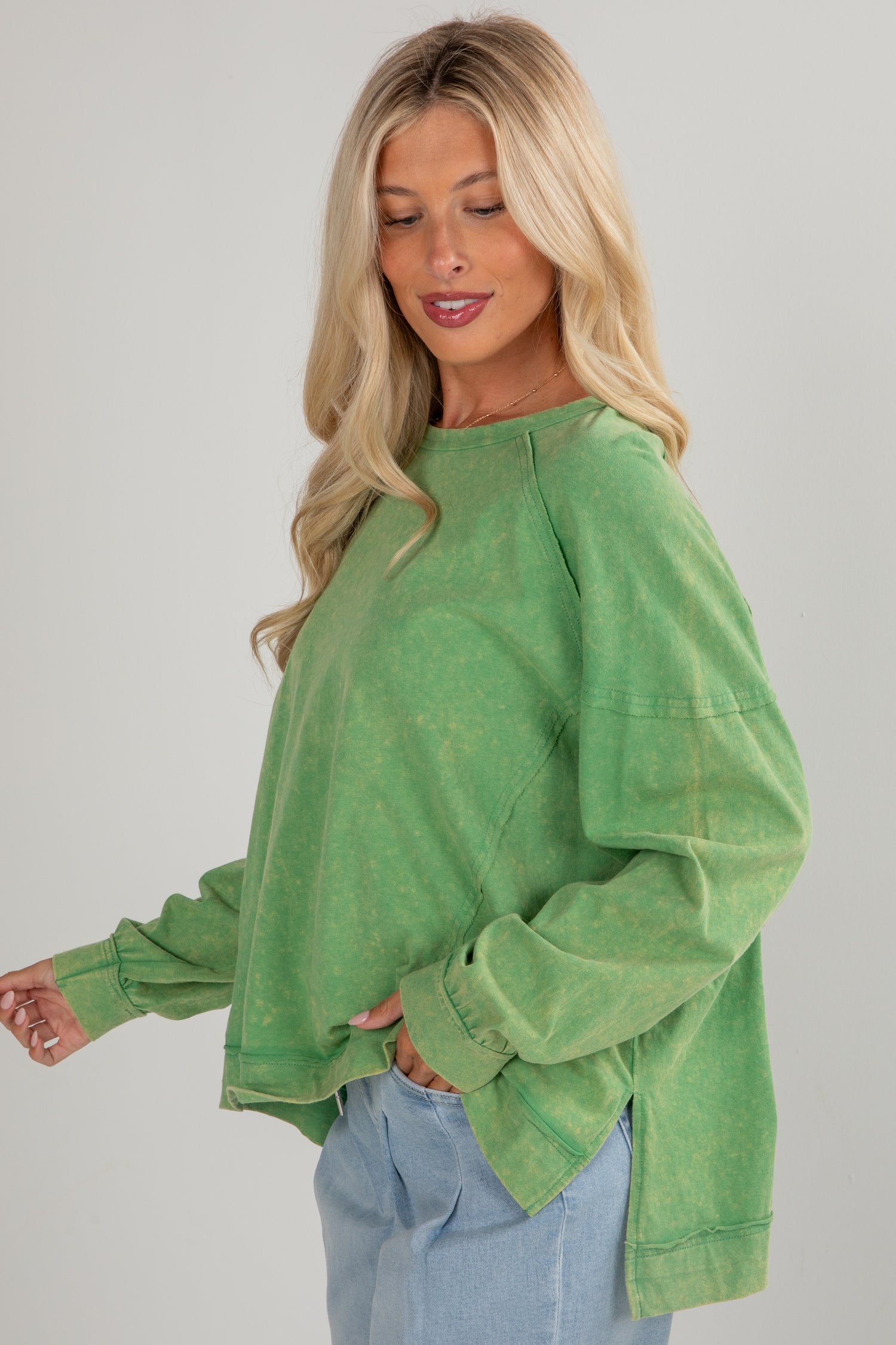 Woman wearing a green oversized sweater against a plain background